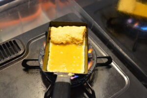 alt="卵焼きを焼いている途中の様子｜フライパンで巻いている工程"